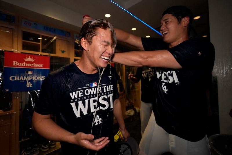 Los Angeles Dodgers designated hitter Shohei Ohtani, right, douses teammate starting pitcher Yoshinobu Yamamoto, left, after the Dodgers defeated the San Diego Padres 7-2 in a baseball game to clinch the National League West division Thursday, Sept. 26, 2024, in Los Angeles. (AP Photo/Ashley Landis)