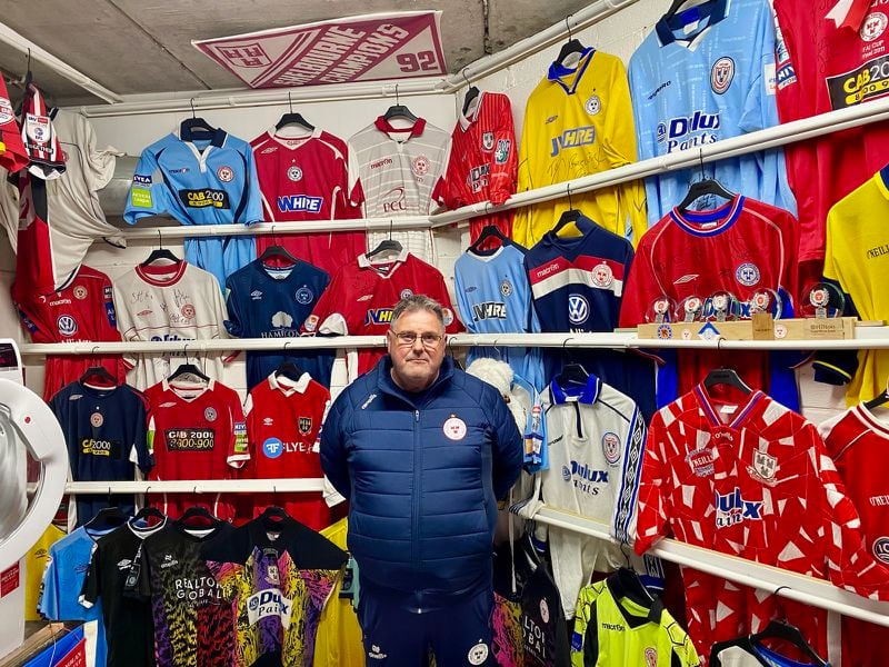 Shelbourne F.C. kit man Johnny Watson poses in front of a wall of jerseys in the laundry room at Tolka Park stadium in Drumcondra, Ireland, Aug. 23, 2024. The jerseys commemorate significant matches in the club's history. Drumcondra is a suburb of Dublin.