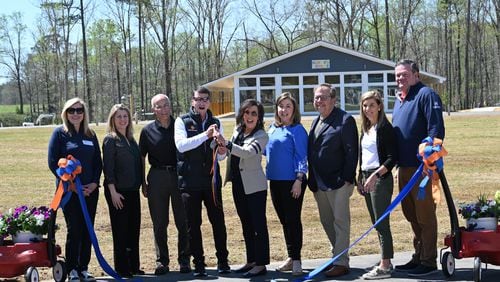 Doug Hertz (center left), founder and board chair, and Elizabeth Correll Richards (center right) hold up a pair of scissors after cutting the ribbon during the grand opening ceremony on the new campus at Camp Twin Lakes, Thursday, March 30, 2023, in Rutledge. For 30 years, Georgia children with serious illnesses, disabilities and other challenges have had access to a full camp experience at Camp Twin Lakes. On Thursday, the camp celebrated a $25 million expansion that will allow 3,500 more campers to attend each year, including some whom the camp was previously unable to serve. (Hyosub Shin / Hyosub.Shin@ajc.com)