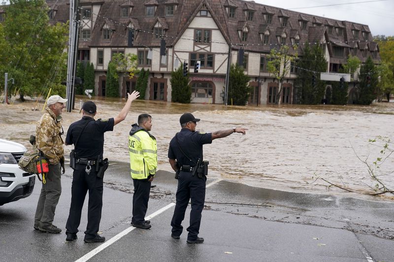 Emergency personnel watch as floodwaters rise, Friday, Sept. 27, 2024, in Asheville, N.C. (AP Photo/Erik Verduzco)