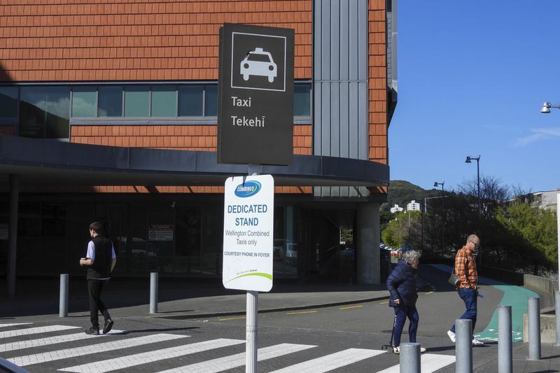 People cross a road near a taxi stand written in English and Maori languages as New Zealand celebrates its annual Maori language week in Wellington, New Zealand, Wednesday, Sept. 18, 2024. (AP Photo/Charlotte GrahamMcLay)