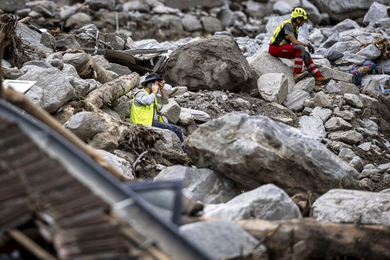 Rescue workers take a break at the site of a landslide, caused by severe weather and heavy rain in the Misox valley, in Sorte village, Lostallo, southern Switzerland on Sunday June 23, 2024. Authorities in Switzerland say rescuers have found the body of one of three people who had gone missing on Saturday after massive thunderstorms and rainfall in the southeast of the county caused a rockslide. (Michael Buholzer/Keystone via AP)