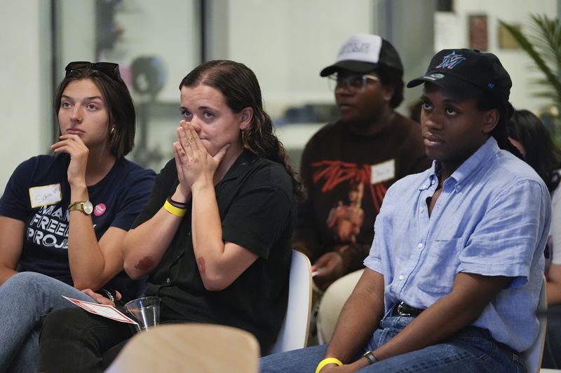 People react as they watch the debate between President Joe Biden and his Republican rival, former President Donald Trump, at a watch party organized by the Miami Freedom Project at the Center for Black Innovation in Overtown, Miami, Thursday, June 27, 2024. (AP Photo/Rebecca Blackwell)