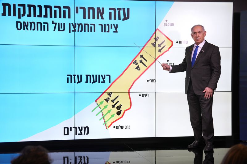 Israeli Prime Minister Benjamin Netanyahu stands before a map of the Gaza Strip, telling viewers how Hamas has imported arms into the territory since Israel's withdrawal in 2005, during a news conference in Jerusalem, Monday, Sept. 2, 2024. The Hebrew on the screen reads, "Gaza after the disengagement, oxygen pipe of Hamas". (AP Photo/Ohad Zwigenberg, Pool)