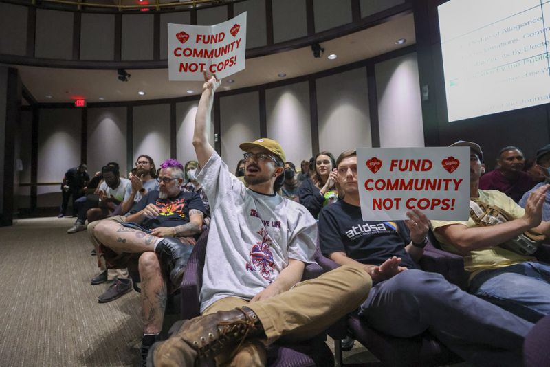 Protestors hold a “Fund Community Not Cops!,” sign during the public comment portion of the Atlanta City Council ahead of the final vote to approve legislation to fund the training center at Atlanta City Hall, on Monday, June 5, 2023, in Atlanta. (Jason Getz / Jason.Getz@ajc.com)