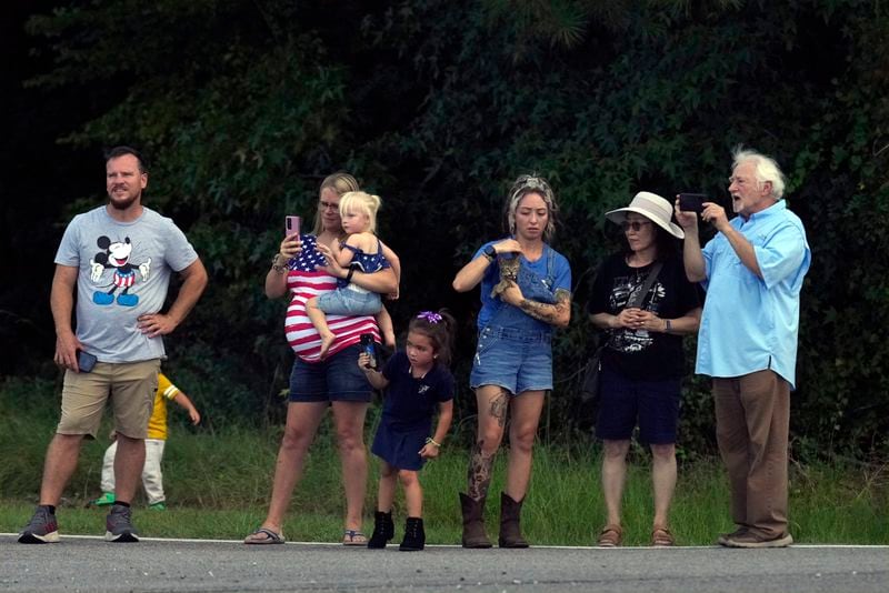 People watch as the bus with Democratic presidential nominee Vice President Kamala Harris and Democratic vice presidential candidate Minnesota Gov. Tim Walz passes by on the way to Liberty County High School in Hinesville, Ga., Wednesday, Aug. 28, 2024. (AP Photo/Jacquelyn Martin)