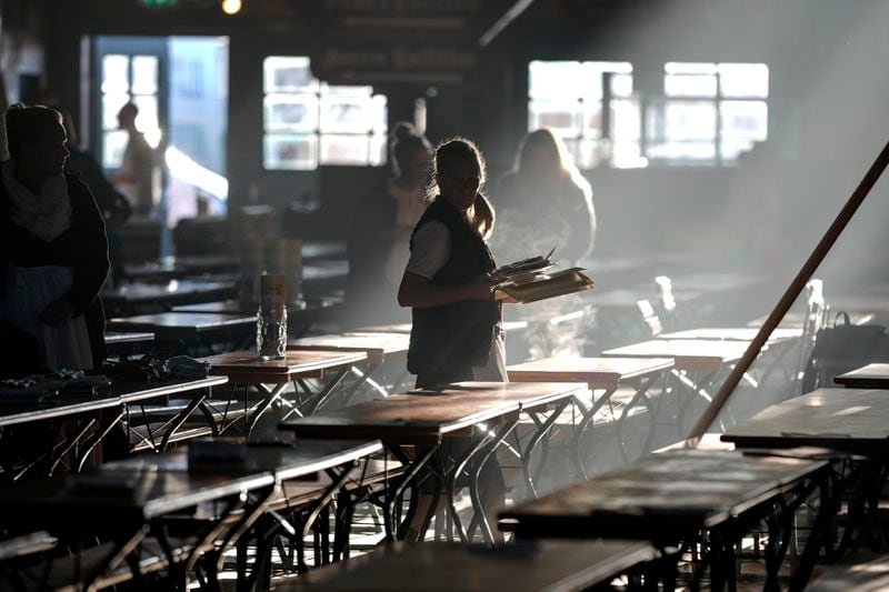 A waitress prepares tables in a marquee for the start of the 189th 'Oktoberfest' beer festival in Munich, Germany, early Saturday morning, Sept. 21, 2024. (AP Photo/Matthias Schrader)