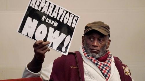 FILE - Morris Griffin holds up a sign during a meeting by the Task Force to Study and Develop Reparation Proposals for African Americans in Oakland, Calif., Dec. 14, 2022. (AP Photo/Jeff Chiu, File)