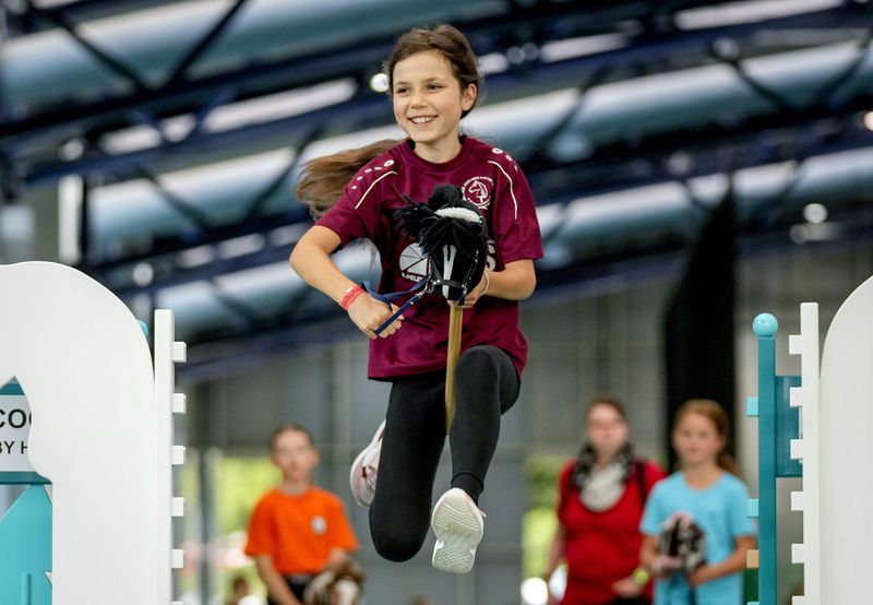 A girl clears the bar during the first German Hobby Horsing Championship in Frankfurt, Germany, Saturday, Sept. 14, 2024. (AP Photo/Michael Probst)