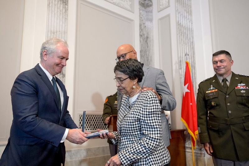 Sen. Chris Van Hollen, D-Md., left, presents the Distinguished Service Cross to Joann Woodson, center, and her son Steve Woodson, right, during a ceremony to posthumously award the Distinguished Service Cross to her husband U.S. Army Staff Sgt. Waverly Woodson, Jr., a medic who was part of the only Black combat unit to take part in the D-Day invasion of France during World War II, on Capitol Hill, in Washington, Tuesday, Sept. 24, 2024. (AP Photo/Rod Lamkey, Jr.)