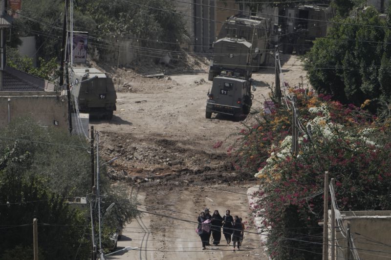 Palestinians walk down a street as they leave the West Bank Jenin refugee camp during an Israeli military operation, Saturday, Aug. 31, 2024. (AP Photo/Majdi Mohammed)