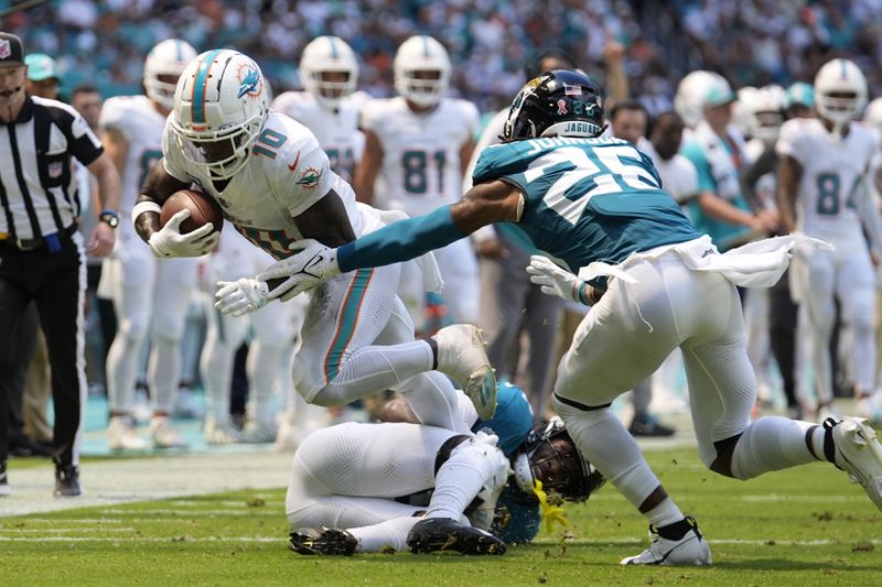 Jacksonville Jaguars cornerback Jarrian Jones (22) and safety Antonio Johnson (26) attempt to stop Miami Dolphins wide receiver Tyreek Hill (10) during the first half of an NFL football game, Sunday, Sept. 8, 2024, in Miami Gardens, Fla. (AP Photo/Rebecca Blackwell)