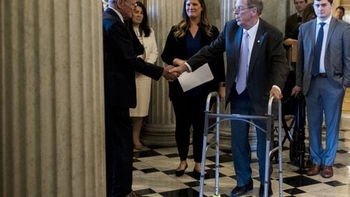 U.S. Sen. Johnny Isakson, R-Ga., right, shakes hands with U.S. Sen. Jim Inhofe, R-Okla., as he walks to the Senate floor to deliver his farewell address Tuesday in the Capitol. Isakson is stepping down at the end of the year for health reasons. (Photo By Bill Clark/CQ Roll Call via AP Images)