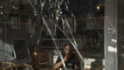 A man eats breakfast in a cafe near the scene of a deadly explosion in Tel Aviv, Israel, Friday, July 19, 2024.(AP Photo/Oded Balilty)