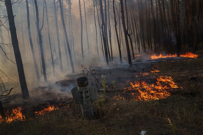 MSLR rocket stick is seen in the ground in a forest fire after a Russian strike near Sloviansk, Donetsk region, Ukraine, on Saturday, Aug. 24, 2024. (AP Photo/Evgeniy Maloletka)