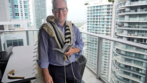 Daniel Gammerman poses for a photo on his balcony where he sometimes prays as he prepares to worship at home for the Jewish High Holy Days, Thursday, Sept. 26, 2024, in Miami. (AP Photo/Wilfredo Lee)