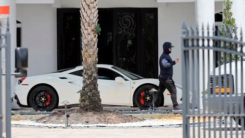 A man walks past a Ferrari in the driveway at Sean Kingston's home in the suburb of Southwest Ranches, Fla., Thursday, May 23, 2024. A SWAT team raided rapper Kingston's rented mansion on Thursday, and arrested his mother on fraud and theft charges that an attorney says stems partly from the installation of a massive TV at the home. Broward County detectives arrested Janice Turner, 61, at the home. (Amy Beth Bennett/South Florida Sun-Sentinel via AP)