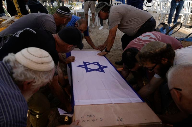 Relatives and friends place the coffin of Yoram Metzger in his grave during his funeral at a cemetery of the kibbutz Nir Oz, southern Israel, Thursday, Aug. 22, 2024. Metzger's body was one the six bodies of hostages, taken in Hamas' Oct. 7 attack, recovered by Israel's military during an operation in the Gaza Strip. (AP Photo/Tsafrir Abayov)