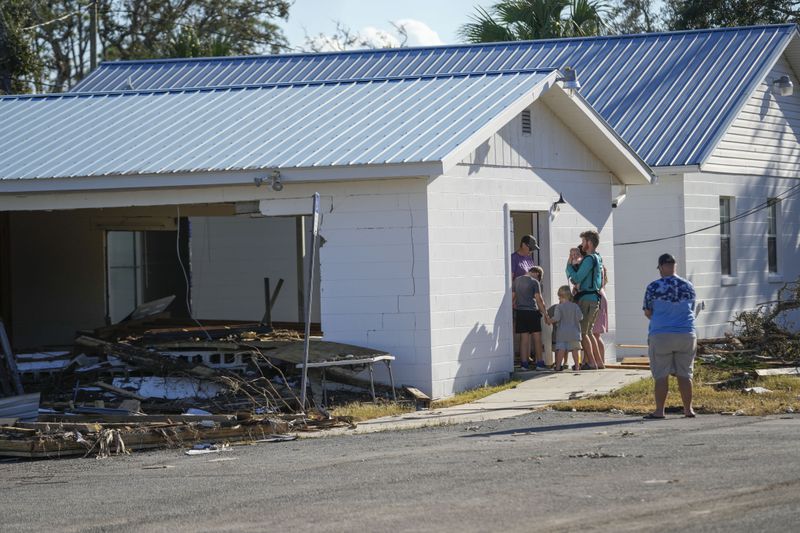 A group from St. Augustine, Fla. that arrived to help storm victims, who did not want to give their name, pray outside the damaged First Baptist Church in the aftermath of Hurricane Helene, in Horseshoe Beach, Fla., Sunday, Sept. 29, 2024. (AP Photo/Gerald Herbert)