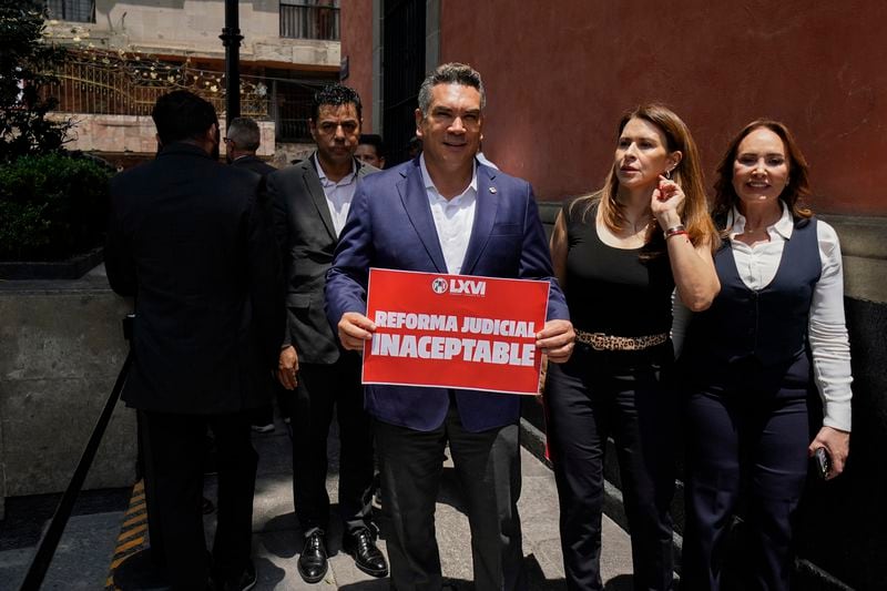 Alejandro Moreno, Institutional Revolutionary Party leader, holds a sign with a message that reads in Spanish: "Judicial Reform unacceptable", outside an alternate headquarters for senators who are discussing the reform one day after Mexico's lower house approved it, in Mexico City, Thursday, Sept. 5, 2024, (AP Photo/Felix Marquez)