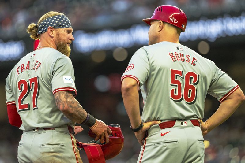 Cincinnati Reds' Jake Fraley (27) talks with third base coach J.R. House (56) between batters in the fourth inning of a make-up baseball game against the Atlanta Braves, Monday, Sept. 9, 2024, in Atlanta. (AP Photo/Jason Allen)