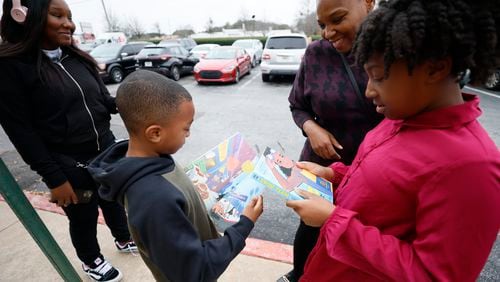 Savannah (right) and Logan Zachery select books from the Little Free Library at Eggs Up Grill in Morrow as their mother, Jennitra, approves their choices. The books are part of the Read in Color program, which focuses on books with diverse characters and authors. (Miguel Martinez / miguel.martinezjimenez@ajc.com)