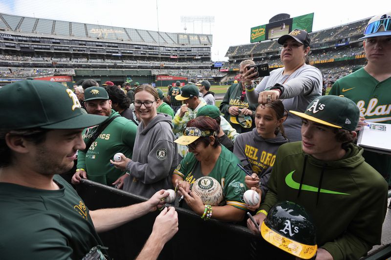 Oakland Athletics' Jacob Wilson, left, sign autographs for fans before a baseball game against the Texas Rangers, Thursday, Sept. 26, 2024, in Oakland, Calif. (AP Photo/Godofredo A. Vásquez)