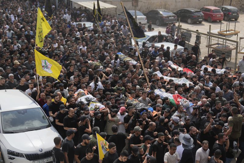 Mourners carry the bodies of Palestinian men who were killed during an Israeli military operation, some draped in the Palestinian flags and the Islamic Jihad militant group, during their funeral in Jenin, West Bank, Friday, Sept. 6, 2024. (AP Photo/Nasser Nasser)