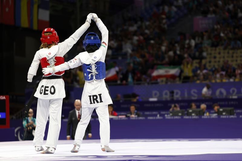 Iran's Zahra Rahimi, right, lifts up Georgia's Ana Japaridze's arm after beating her, 6-0, in a K44 match during the Paralympic Games in Paris on Thursday, Aug. 29, 2024. (AP Photo/Madeleine Mertens)