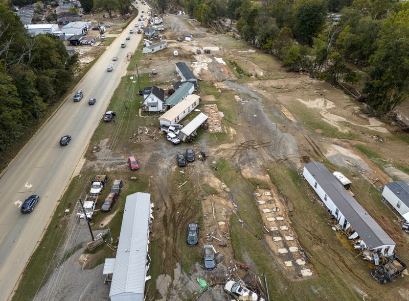 Homes and vehicles that were damaged in a flash flood from Hurricane Helene lie on the side of a road near the Swannanoa River, Tuesday, Oct. 1, 2024, in Swannanoa, N.C. (AP Photo/Mike Stewart)