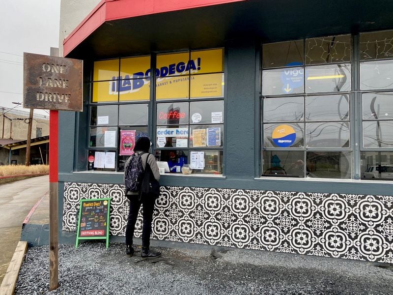 A customer orders from the walk-up window at La Bodega Market & Pupuseria. Wendell Brock for The Atlanta Journal-Constitution