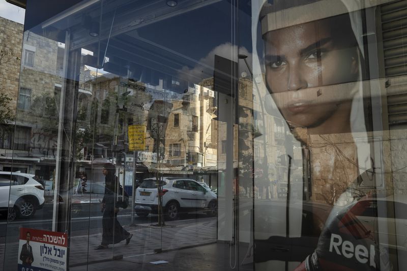 A woman walks past a closed shop in Haifa, Israel, Thursday, Aug. 15, 2024. (AP Photo/Leo Correa)