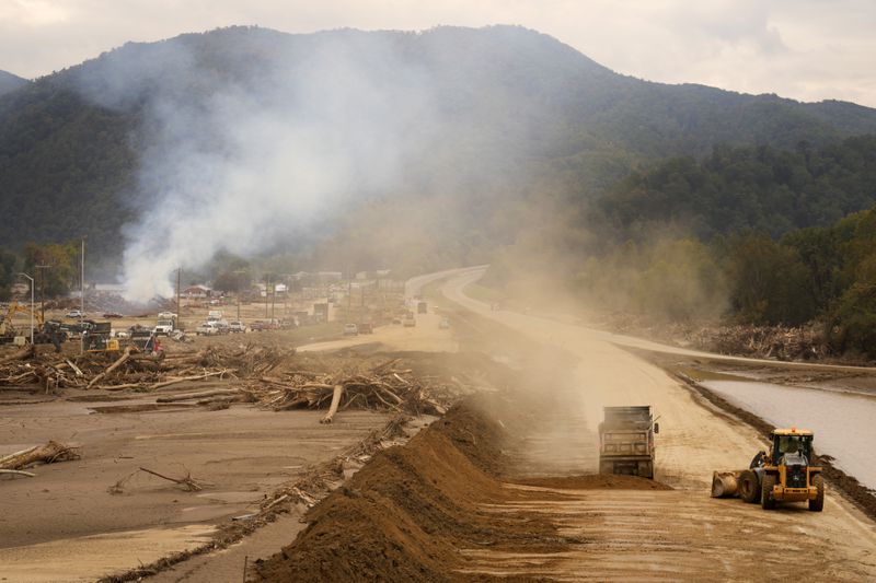 Heavy machinery is used to clear Interstate 26 as debris is burned in the background following Hurricane Helene Friday, Oct. 4, 2024, in Erwin, Tenn. (AP Photo/Jeff Roberson)