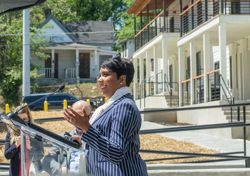 At the formal ribbon cutting of Home on The Westside, Mayor Keisha Lance Bottoms, at podium, addresses the crowd Wednesday, April 21, 2021, during the ceremony at Home on The Westside housing complex built for long-time Westside residents who need affordable housing.  The house across the street from the complex is still abandoned and boarded up. (Jenni Girtman for The Atlanta Journal-Constitution)