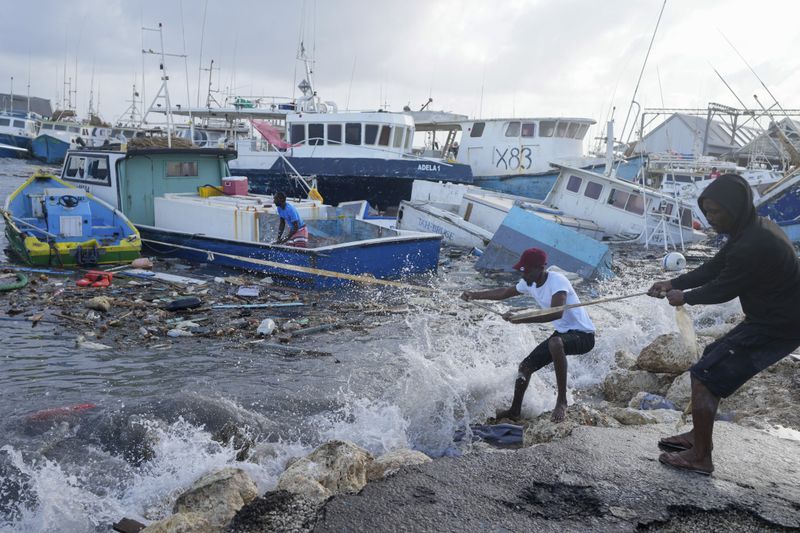 Fishermen pull a boat damaged by Hurricane Beryl back to the dock at the Bridgetown Fisheries in Barbados, Monday, July 1, 2024. (AP Photo/Ricardo Mazalan)