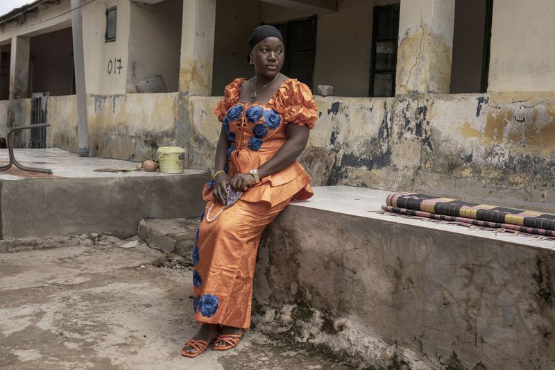 Binta Bah, whose husband Suleyman works in a factory in Germany, poses for a portrait outside her house in the village of Kwinella, Gambia, on July 27, 2024. (AP Photo/Annika Hammerschlag)