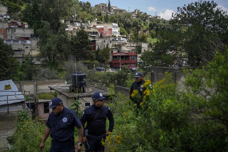 Municipal police officers guard the area where various people died after a rain-induced landslide, in Naucalpan, Mexico, Tuesday, Sept. 17, 2024. (AP Photo/Felix Marquez)