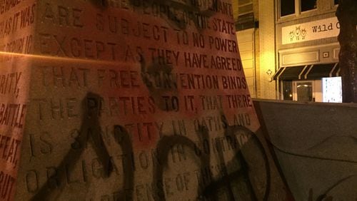 The Confederate monument in Decatur Square is dismantled and removed after midnight on June 19, 2020. The base of the monument, shown here loaded on a truck on Ponce de Leon Ave. following its removal, was engraved on all four sides with text glorifying the Confederacy. One side is engraved “ERECTED by the men and women and children of DeKalb County to the memory of the soldiers and sailors of the Confederacy, of whose virtues in peace and in war we are witnesses to the end that justice may be done and that the truth perish not. Graffiti painted over the text on two other sides that called Confederates “a covenant keeping race who held fast to the faith as it was given by the fathers of the Republic” and who believed that “there is sanctity in oaths and obligation in contracts” (that side shown here), apparent references to the original U.S. Constitution, which provided for states to allow slavery. The graffiti on those two sides is a background of red paint with a black stencil of the face of George Floyd in the center. This side is also painted with the words “RIP Floyd”. (PHOTO by Ariel Hart / ahart@ajc.com)