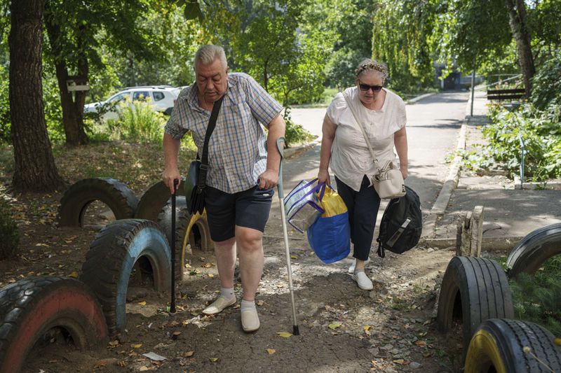 Family walk to a van during evacuation in Selidove, Donetsk region, Ukraine, Monday, August 19, 2024. Due to the advance of Russian troops, the war affects more and more new settlements to the west of the Donetsk region. Intensive shelling forced people to leave homes. (AP Photo/Evgeniy Maloletka)