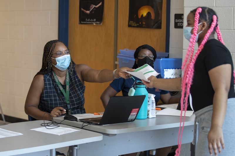 Mundy's Mill High School assistant principal Sharon Wilson hands a student a paperwork for a laptop during a laptop distribution at the school in Jonesboro, Georgia, on Sept. 1, 2020. (Alyssa Pointer / Alyssa.Pointer@ajc.com)