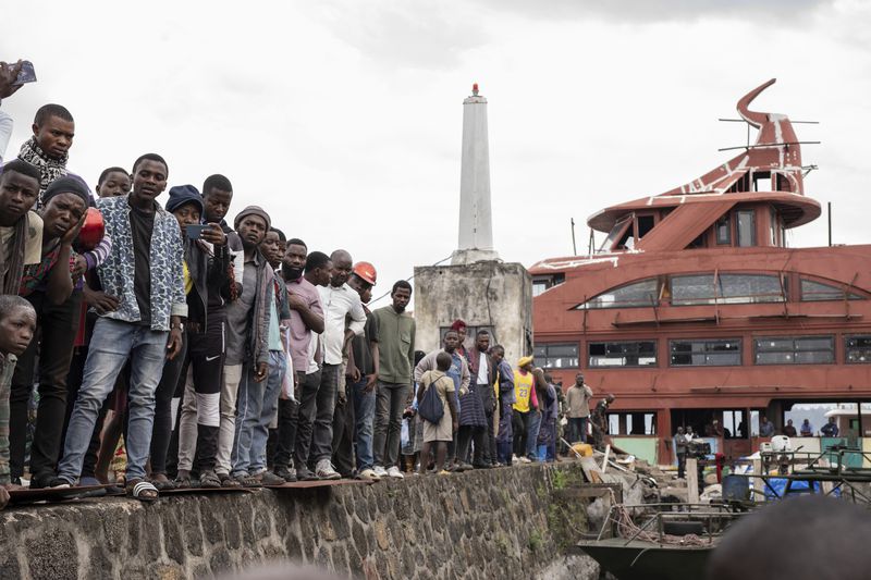 People gather at the port of Goma, Democratic Republic of Congo, after a ferry carrying hundreds capsized on arrival Thursday, Oct. 3, 2024, killing scores. (AP Photo/Moses Sawasawa)