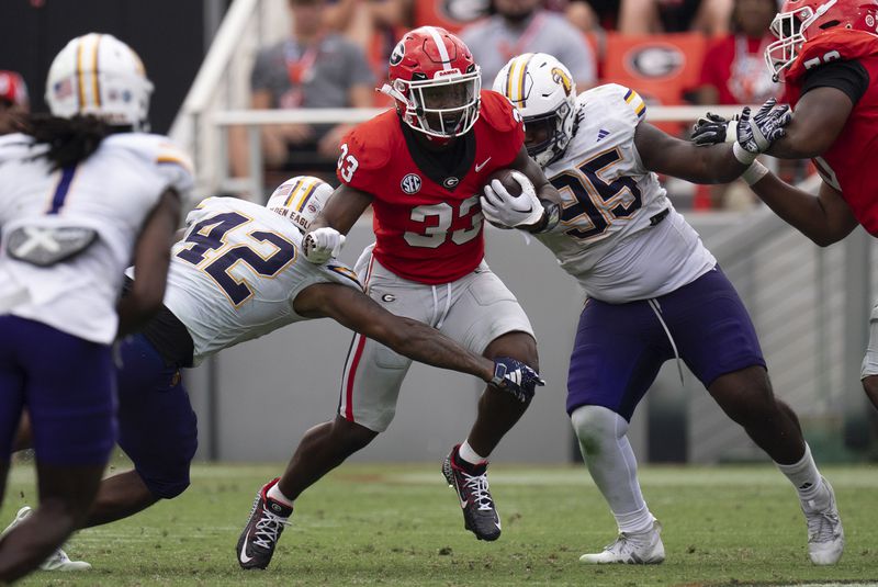 Georgia running back Chauncey Bowers (33) runs between Tennessee Tech linebacker Kalvyn Crummie (42) and defensive lineman Jeremiah Sandiford (95) during the second half of an NCAA college football game Saturday, Sept. 7, 2024, in Athens, Ga. (AP Photo/John Bazemore)