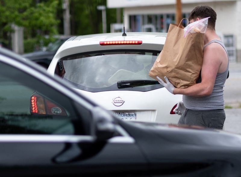Stephen Tate brings a bag of food to a person at the CHRIS 180 drive-up food distribution Friday, April 24, 2020. Ben@BenGray.com for the Atlanta Journal-Constitution