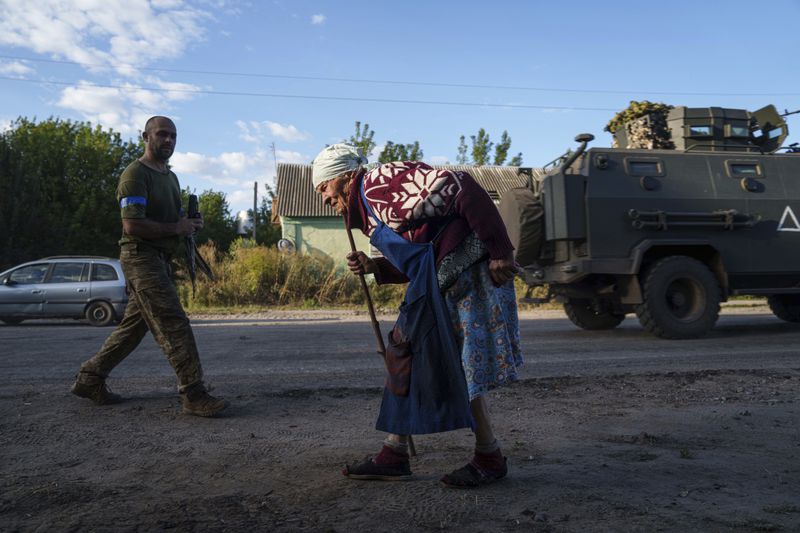 An elderly woman walks along the road near the Russian-Ukrainian border, Sumy region, Ukraine, Wednesday, Aug. 14, 2024. (AP Photo/Evgeniy Maloletka)