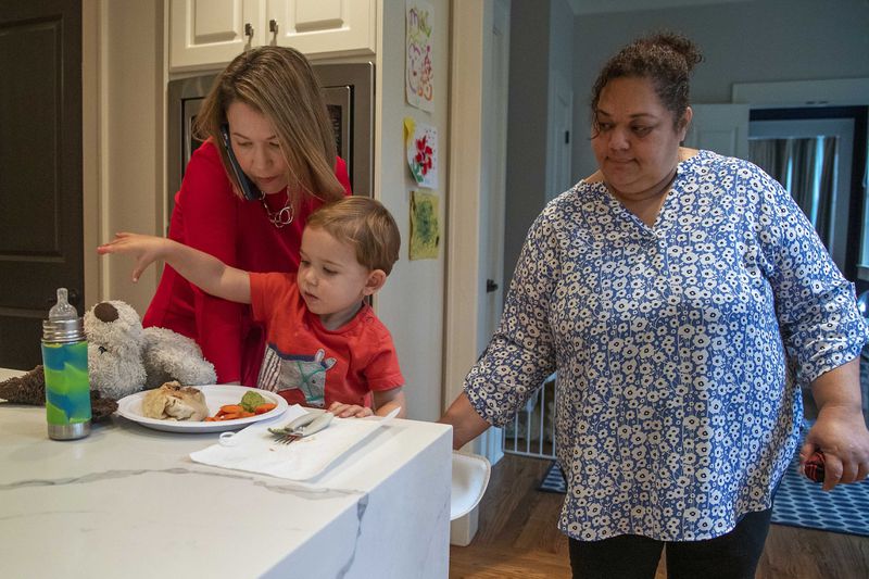 Lyndsey Rudder (left), Republican candidate for state House District 54, is helped by her nanny Olga as they get Maclin, Lyndsey's youngest son, into a seat to eat lunch at her residence in Atlanta on Sept. 14, 2020. Rudder says she is appreciative of the help she receives while navigating this campaign season. (Alyssa Pointer / Alyssa.Pointer@ajc.com)