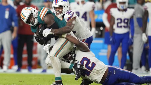 Miami Dolphins running back De'Von Achane is tackled by Buffalo Bills linebacker Dorian Williams (42) and cornerback Rasul Douglas (31) during the second half of an NFL football game, Thursday, Sept. 12, 2024, in Miami Gardens, Fla. (AP Photo/Rebecca Blackwell)