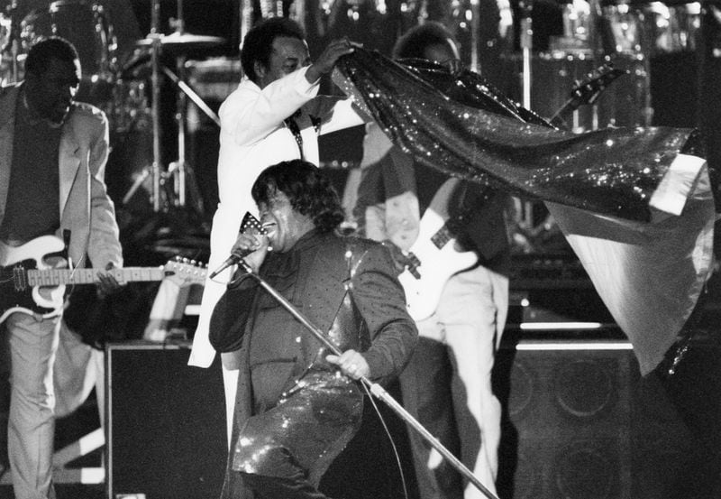 James Brown is caped by one of the band members while performing for the Auburn Avenue Festival in Atlanta, GA on April 17, 1992. (Renee Hannans/AJC staff)