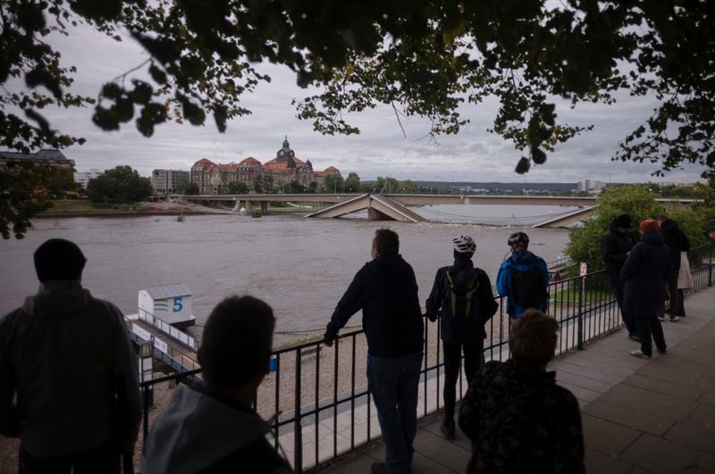 FILE - Spectators look at the partially collapsed Carolabrucke bridge, over the Elbe, which is rising rapidly due floodwaters, in front of the state chancellery in Dresden, Germany, Sept. 15, 2024. (AP Photo/Markus Schreiber)