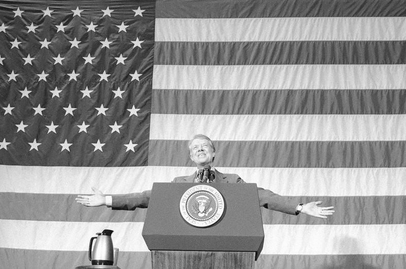 FILE - President Jimmy Carter acknowledges the applause of about 1,100 people gathered in the Elk City High School gym for a town meeting in Elk City, Okla., March 24, 1979. (AP Photo, File)