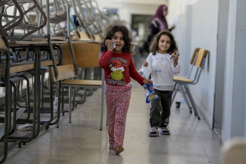 Displaced children play in a classroom at a school, in Beirut, after fleeing the Israeli airstrikes in the south with their families, Thursday, Sept. 26, 2024. (AP Photo/Bilal Hussein)